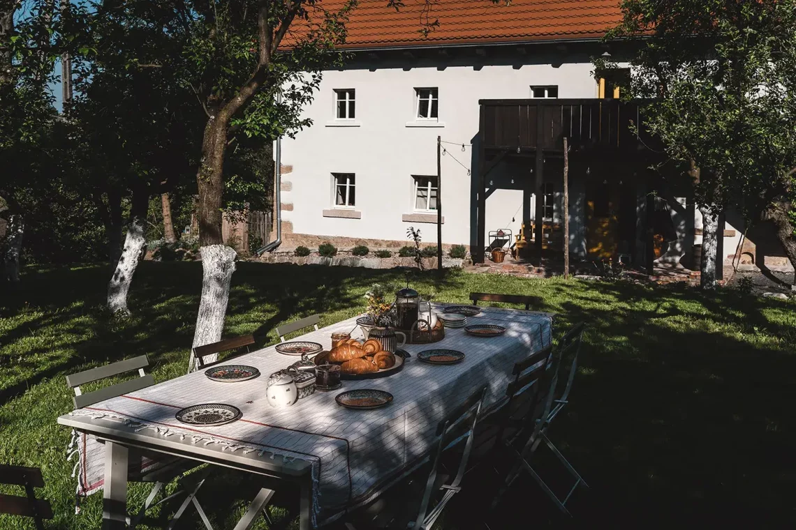 Fotografia wnętrz, widok na budynek Wietorówce, a przed nim stół biesiadny